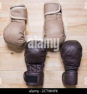 I guanti da combattimento neri e beige per l'allenamento sportivo si trovano su un tavolo di legno Foto Stock