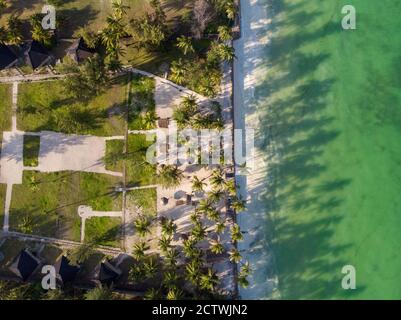 Foto aerea di un hotel di lusso su una spiaggia prima La linea con gli alberi di palma cade le loro tonalità su un alto Marea acqua dell'Oceano Indiano alla sera in Paje Foto Stock