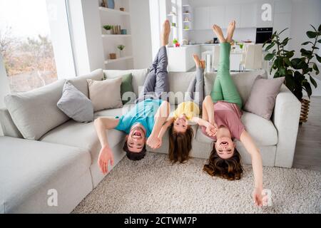 Foto a lunghezza intera di tre persone hanno un fine settimana di relax in famiglia sedersi il divano capovolto tenere la mano in casa al chiuso Foto Stock