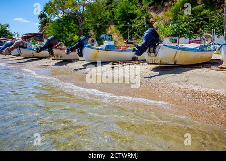 Vista sul mare calmo e sulla spiaggia di sabbia ciottolosa, le barche da pesca sono ormeggiate a secco. Foto Stock