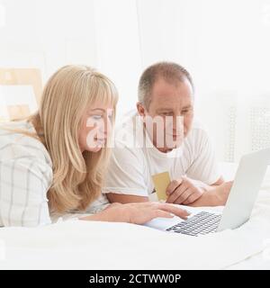 Coppia di famiglia matura che guarda lo schermo del notebook. Felice uomo di mezza età con carta di credito Foto Stock