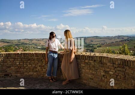 Corinaldo, Marche, Italia - Settembre 24 2020: Una coppia di donne parla su una torre medievale con vista panoramica sullo sfondo Foto Stock