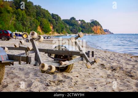 Un rimorchio vuoto è parcheggiato sulla spiaggia di sabbia, in attesa di barche di trasporto. Foto Stock