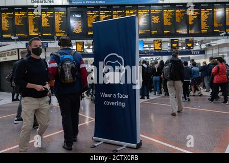 Un grande cartello si trova sull'atrio della stazione ferroviaria principale di Victoria invita i passeggeri e i pendolari a indossare una copertura facciale durante il viaggio sul sistema di trasporto pubblico della capitale, il 24 settembre, a Londra, Inghilterra. Nuove restrizioni sono state reintrodotte dal governo dopo un improvviso aumento del tasso di infezione di Covid, un previsto 'secondo picco'. Solo coloro che hanno problemi medici o psicologici sono esenti da indossare una copertura facciale anche se £200 multe sono in vigore per coloro che violano le regole. Foto Stock