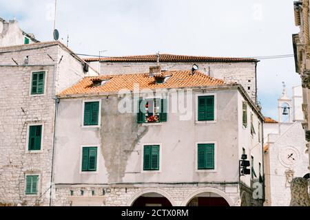 Vecchio edificio residenziale a tre piani con persiane verdi e piastrelle arancioni sul tetto. Foto Stock