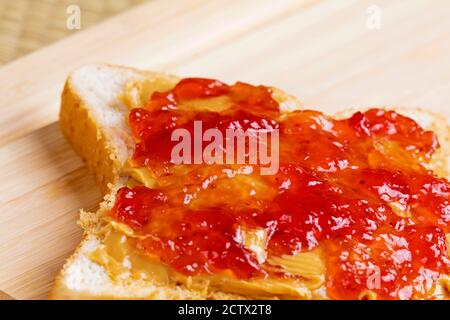 Un gustoso e delizioso panino di burro di arachidi e marmellata su un sfondo di legno Foto Stock