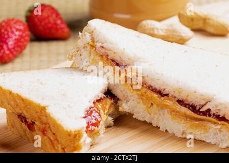 Un gustoso e delizioso panino di burro di arachidi e marmellata su un sfondo di legno Foto Stock