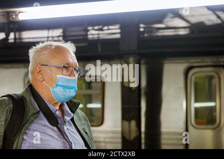 Maschera monouso uomo a faccia nella stazione della metropolitana Covid-19 pandemia epidemica di coronavirus su treno metro tubo maschile assistenza sanitaria messa a fuoco morbida Foto Stock