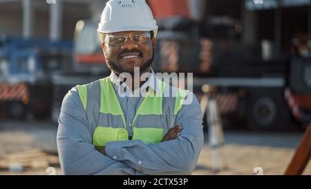 Ritratto di un investitore di successo, un ingegnere architettonico che indossa un casco rigido E giubbotto di sicurezza in piedi in un cantiere di costruzione di edifici commerciali Foto Stock