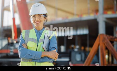 Ritratto di bella donna Architectural Engineer Safety Inspector Investor chiude il laptop, attraversa le braccia sul sito di costruzione commerciale degli edifici Foto Stock