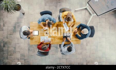 Sala riunioni Startup: Team di imprenditori seduti al tavolo della conferenza hanno discussioni, risolvere problemi, utilizzare Digital Tablet, laptop, condividere Foto Stock