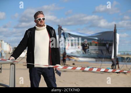 Satirist Cold War Steve, aka Christopher Spencer, a Boscombe Beach, Bournemouth, prima dell'installazione del suo lavoro, un windbreak curvo di 25 metri che raffigura una scena di Bournemouth Beach, come parte del Bournemouth Arts dal Sea Festival 2020. Foto Stock