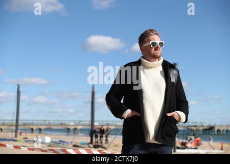 Satirist Cold War Steve, aka Christopher Spencer, a Boscombe Beach, Bournemouth, prima dell'installazione del suo lavoro, un windbreak curvo di 25 metri che raffigura una scena di Bournemouth Beach, come parte del Bournemouth Arts dal Sea Festival 2020. Foto Stock