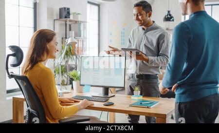 Tre sviluppatori di software mobili lavorano su un computer desktop, parlano di progettazione di applicazioni per smartphone utilizzare il touch screen Digital Tablet. Moderno ed elegante Foto Stock