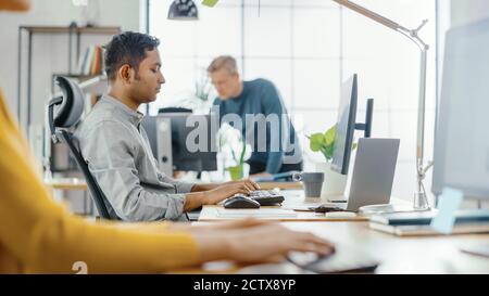 Uomo che lavora al computer. In Foreground Anonymous Young Woman seduto alla sua scrivania utilizzando la tastiera del computer. In background Bright Ufficio dove Foto Stock