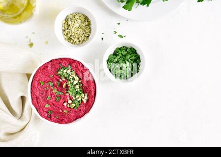 Hummus di barbabietola fatto in casa in ciotola su sfondo bianco di pietra con spazio libero di testo. Vista dall'alto, disposizione piatta Foto Stock