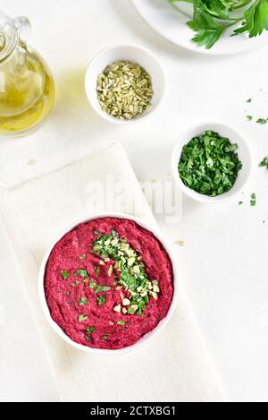 Hummus di barbabietola fatto in casa in ciotola su sfondo di pietra bianca. Vista dall'alto, disposizione piatta Foto Stock