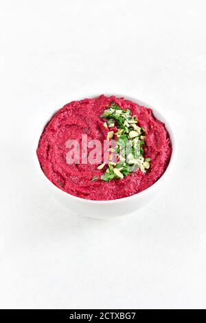 Hummus di barbabietola fatto in casa in ciotola su sfondo bianco di pietra con spazio libero di testo. Foto Stock