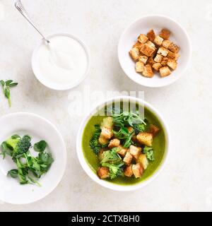 Zuppa di crema di pisello verde di broccoli con crostini in ciotola su sfondo di pietra chiaro. Dieta detox alimentare concetto. Vista dall'alto, piatto Foto Stock