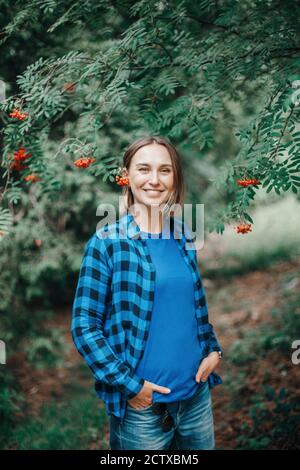 Autunno autunno donna ritratto. Bella felice sorridente donna di mezza età in piedi nel parco con le bacche rosse di rowan sull'orecchio. Stupido momento divertente. Donna dentro Foto Stock