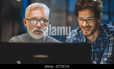 Capo Creative Designer mostra lo schermo del computer desktop a uno sviluppatore giovane, che discute di progetto. Due professionisti che hanno discussione. Scegliere di destra Foto Stock