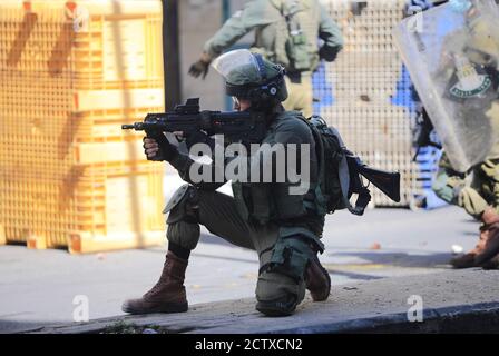 Hebron, città della Cisgiordania di Hebron. 25 Settembre 2020. Un soldato israeliano punta la sua arma ai manifestanti palestinesi durante gli scontri, a seguito di una protesta contro l'espansione degli insediamenti ebraici e gli accordi di normalizzazione di Israele con gli Emirati Arabi Uniti e il Bahrain, nella città di Hebron, in Cisgiordania, il 25 settembre 2020. Credit: Mamoun Wazwaz/Xinhua/Alamy Live News Foto Stock