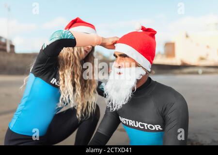 Le coppie sulla spiaggia si aiutano a vestirsi Come Babbo Natale Foto Stock