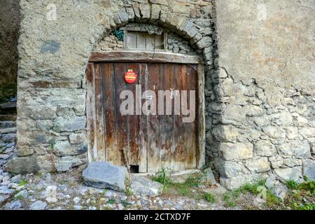 Porta con cartello di avvertenza, in vecchi edifici nel villaggio Puy-Saint-Vincent, stazione sciistica, in estate, Parco Nazionale Vanoise, Ecrins, Francia Foto Stock