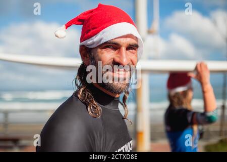 Interessanti gli istruttori di surf giovane a piedi con i loro tavola da surf lungo la passeggiata sul lungomare Foto Stock