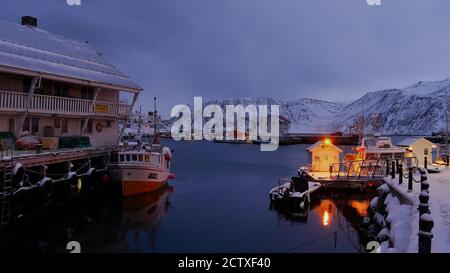 Foto di un'ora blu prima del buio del porto illuminato con navi da pesca a Honningsvag, Norvegia in inverno. Foto Stock