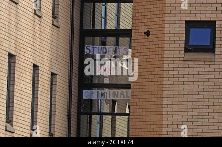 Uno studente passa accanto a un cartello al Murano Street Student Village di Glasgow, dove gli studenti della Glasgow University vengono testati in un centro di test pop-up. Venerdì in Scozia sono entrate in vigore una serie di nuove misure per combattere l'aumento dei casi di coronavirus, tra cui il divieto di visitare le famiglie al coperto e un coprifuoco per pub e ristoranti. Foto Stock