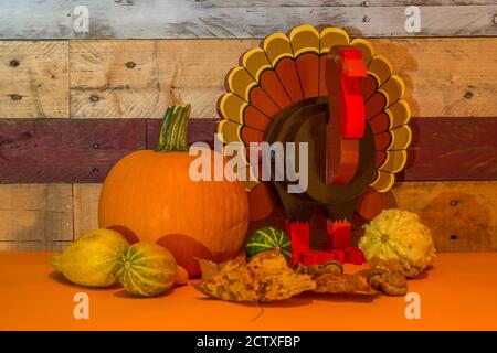 Festa del ringraziamento con una zucca gourds foglie d'autunno e. si accora a fianco di un tacchino di legno lavorato a mano contro un pallet rustico sfondo a parete Foto Stock