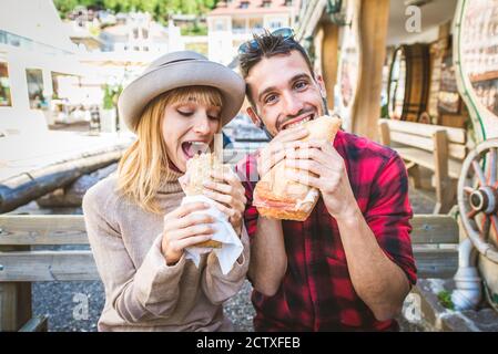 Bella giovane coppia seduta in un bar ristorante e mangiare un sandwich Foto Stock