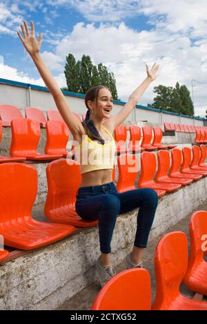 Bella ragazza tifoso tifoso tifoso è felice mentre da solo guardando la partita allo stadio. Foto Stock