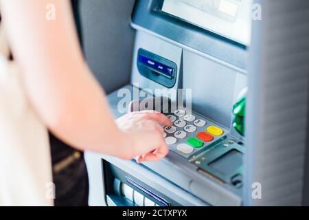 Primo piano di una persona che immette il codice PIN utilizzando un bancomat per prelevare denaro contante. Foto Stock