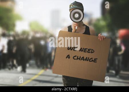 proteste pubbliche e rivolte nelle strade della città. donna con megafono e cartellone in mano sui manifestanti sfondo folla. concetto di democrazia Foto Stock