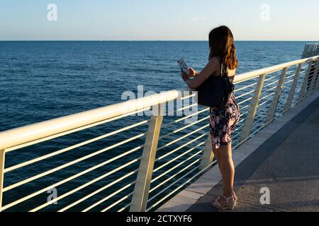 La ragazza parla con gli amici mentre guarda il bellissimo mare toscano. Foto Stock