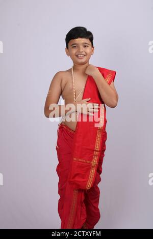 Carino ragazzo indiano in abito etnico svla e uparna - dhoti e stole. Tenendo la sua stola. Foto Stock