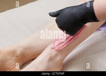 Primo piano di Beautician Waxing Woman's leg in Beauty Spa Foto Stock