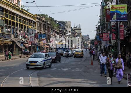 Kolkata, India - 2 febbraio 2020: Un tram di trasporto pubblico e un taxi giallo tradizionale guida nel traffico con pedoni non identificati sul si Foto Stock