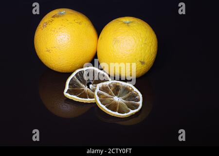 Arance fresche e fette secche su sfondo nero Foto Stock