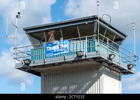 Blackbushe Airport, Hampshire, Regno Unito. 25 settembre 2020. La zona di NHS Surrey Heath ha cominciato a fornire i jab liberi dell'influenza (vaccinazioni dell'influenza) a partire dal gruppo degli anni '70. Queste attività vengono svolte presso una struttura esterna che attraversa l'aeroporto di Blackbushe, appena oltre il confine dell'Hampshire. Un banner di ringraziamento NHS nella parte superiore della torre di controllo Airfieild. Foto Stock