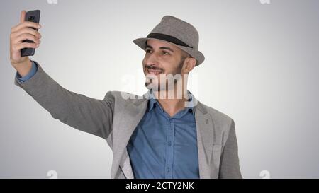 Uomo arabo nei vestiti casual a piedi e facendo selfie su g Foto Stock