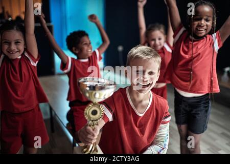 I piccoli giocatori di calcio che celebrano la vittoria in un armadietto camera Foto Stock