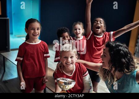 I piccoli giocatori di calcio e allenatore theire celebrano la vittoria in un armadietto Foto Stock