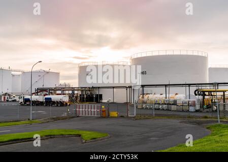 Enormi serbatoi di carburante bianchi in un porto al tramonto Foto Stock