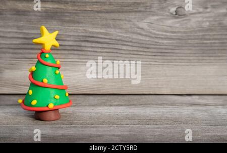 Allegro Natale concetto di argilla. Colorato albero di Natale in miniatura fatto a mano per Natale di fronte a legno morbido sfondo. Spazio di copia. Foto Stock