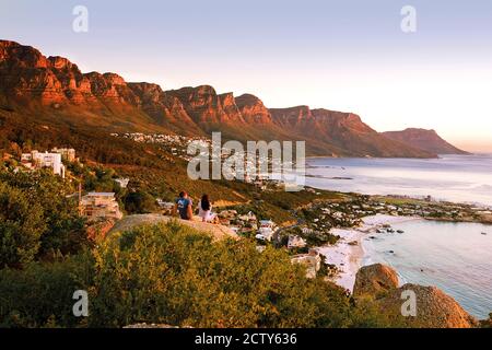 Coppia seduta sulla roccia che si affaccia sulla catena montuosa dei dodici Apostoli e Clifton Beach, Città del Capo, Sud Africa Foto Stock