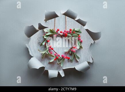 Foro di carta con corona di Natale a forma di mistletoe con bacche rosse, ornamento tradizionale di Natale. Foto Stock