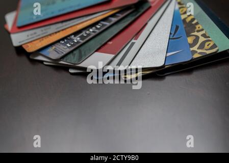 Carte di credito diverse impilano sulla parte superiore del tavolo di legno marrone scuro. Foto Stock